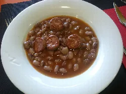 Plato de judías pintas con chorizo en un bol blanco.