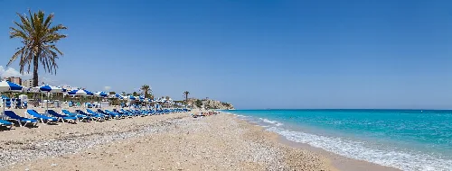 Strand mit goldenem Sand, Sonnenliegen und Palmen in Villajoyosa.