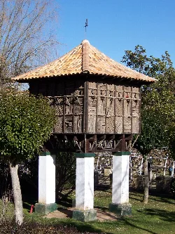 Wooden dovecote in a park with trees and blue sky.