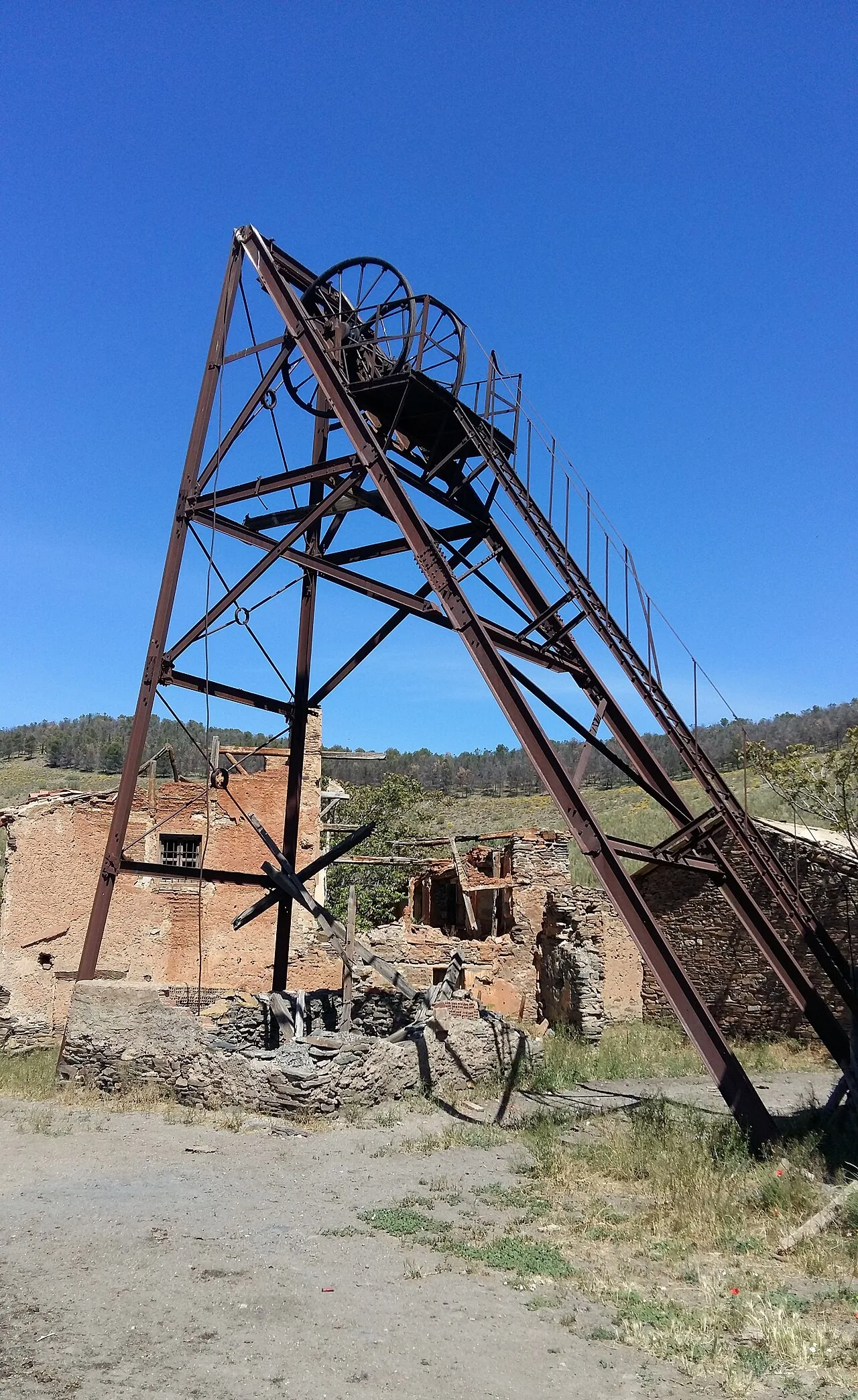 Old mine shaft structure with blue sky and ruins.