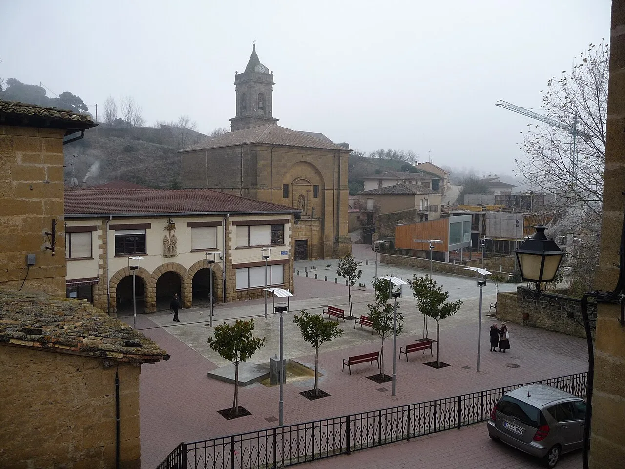 Platz mit Bäumen, Bänken und einer Kirche im Hintergrund in Villabuena de Álava.