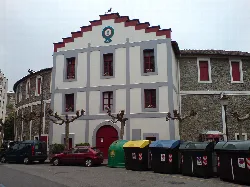 Gebäude in Tolosa mit roten Fenstern und Tür und beschnittenen Bäumen.