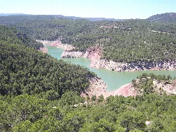 Vista de un embalse con agua azul y colinas verdes alrededor.
