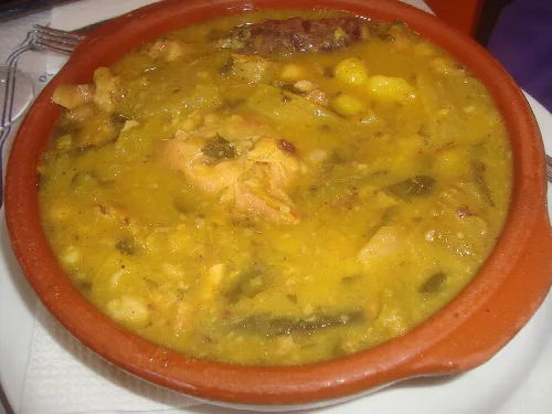 Guiso en plato de barro con garbanzos, verduras y carne.