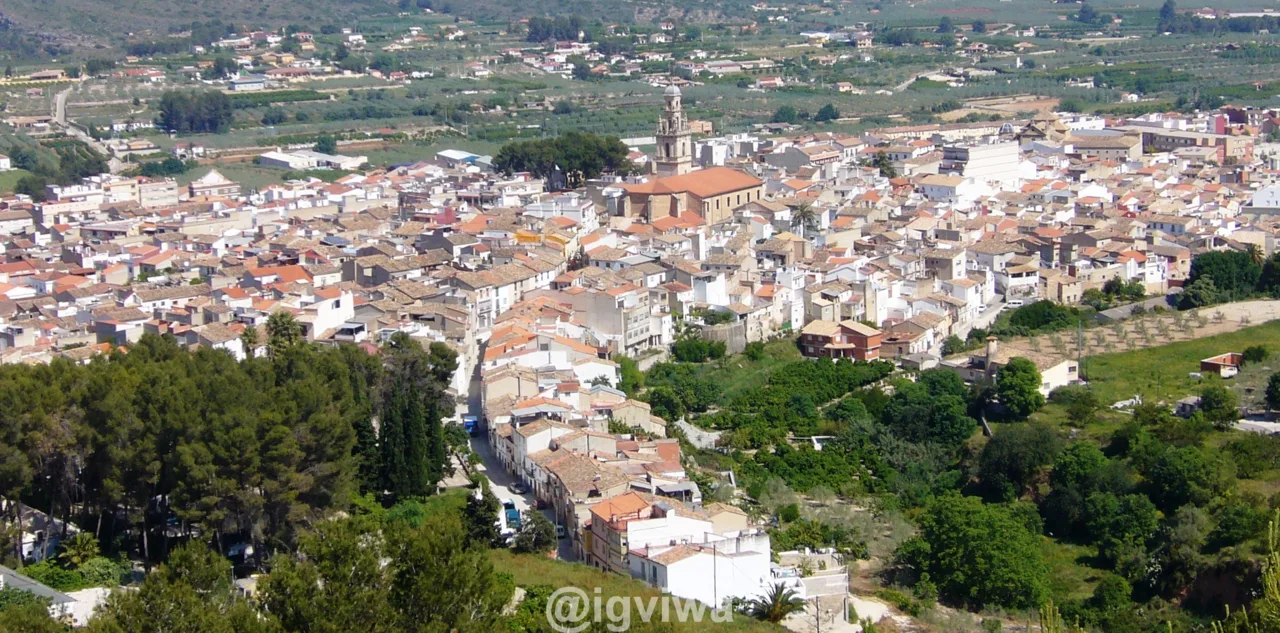 Aerial view of Enguera with streets and white buildings surrounded by greenery.