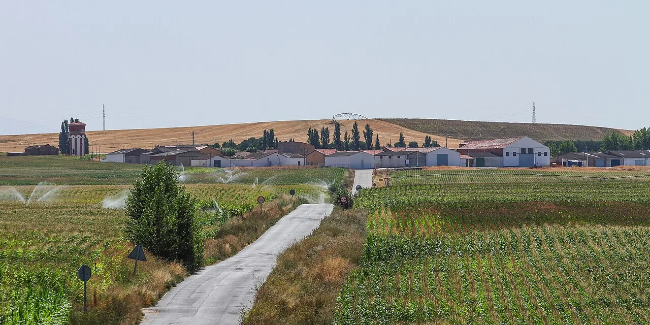 Ländliche Straße mit Feldern und einigen Häusern in der Ferne in Cordovilla.