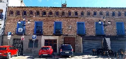 Brick building with blue windows and balconies in the square.