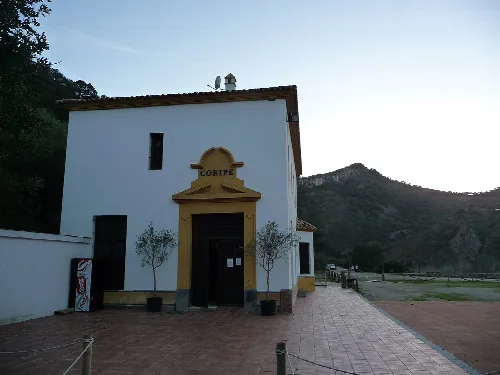 White building in Coripe with entrance decorated with plants and sign.