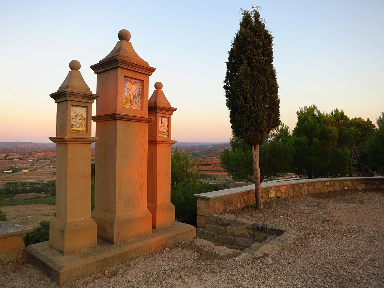 Tres columnas con azulejos y un árbol en un mirador en Castelserás.