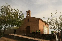 Small church with bell tower and trees around in Villarreal de San Carlos.