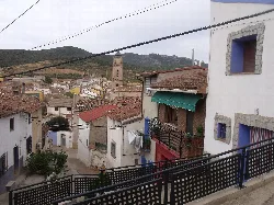 Vista del pueblo con casas y una iglesia en el fondo desde un parque.