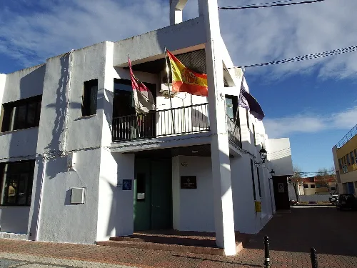 Edificio blanco con banderas en un balcón en Higueruela.