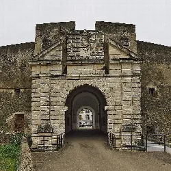 Puerta de piedra con arco en Olivenza, con murallas y estructura de baluarte.