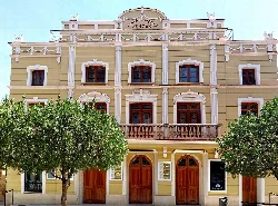 Facade of the Concha Segura Theatre in Yecla, Murcia, with trees in the foreground.