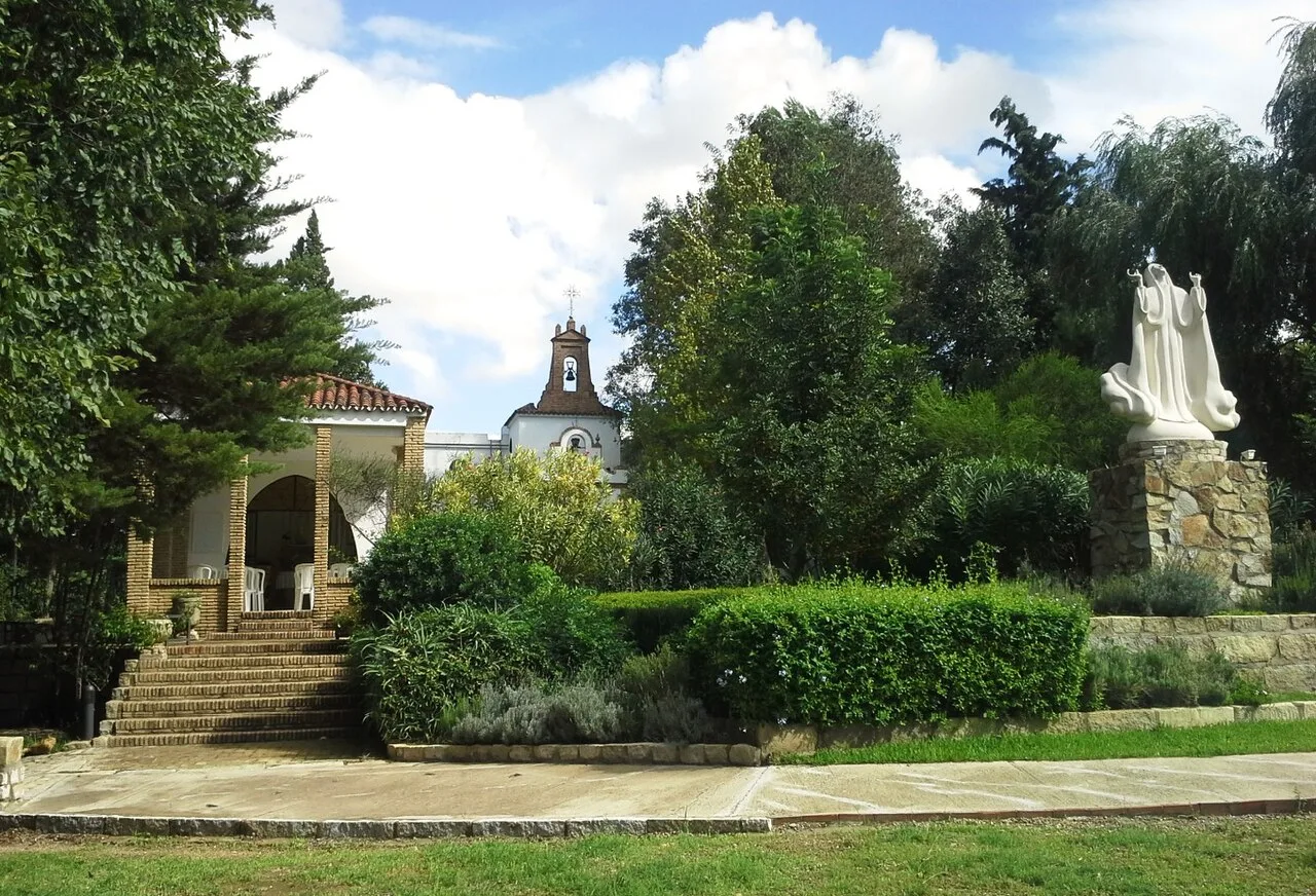 Heiligtum mit Treppen, Bäumen und Statue im Garten.