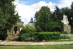 Heiligtum mit Treppen, Bäumen und Statue im Garten.