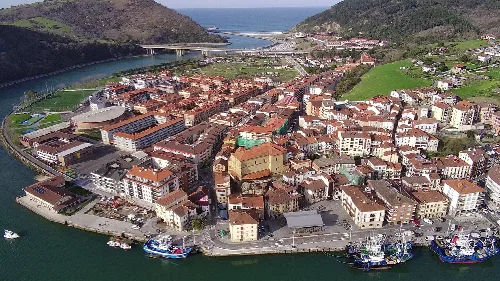 Luftaufnahme von Orio mit Hafen, Straßen und Bergen.