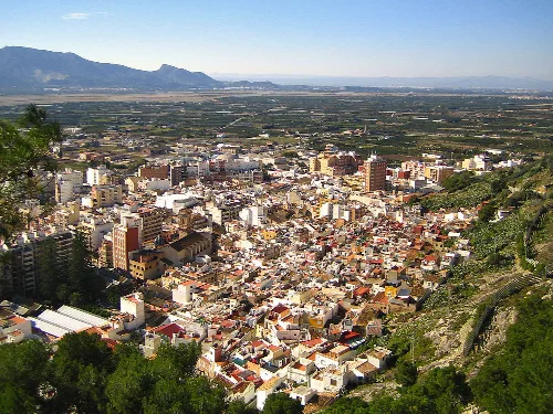 Luftaufnahme von Cullera mit Gebäuden und Bergen im Hintergrund.