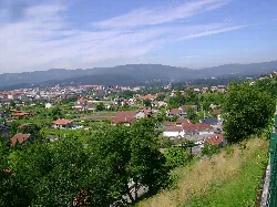Landscape with houses, trees, and distant mountains.