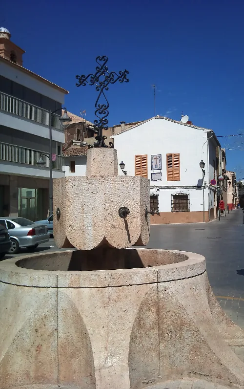 Steinbrunnen mit Kreuz auf der Spitze in Llombai.