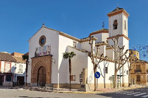 Weiße Kirche mit Turm und geschnittenen Bäumen in Chauchina.