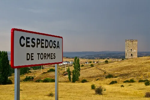Señal de Cespedosa de Tormes en Salamanca con paisaje rural y torre en el fondo.