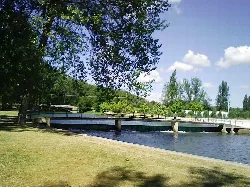 Piscinas naturales en el río Nela con árboles y puente en Villarcayo.