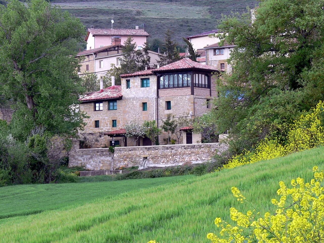 Casas tradicionales en Galbárruli con árboles y campos verdes.