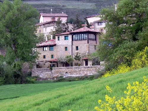 Casas tradicionales en Galbárruli con árboles y campos verdes.