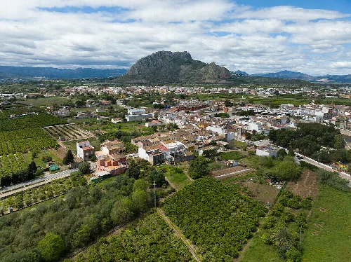 Landschaft mit Häusern, Feldern und einem Berg im Hintergrund in Els Poblets, Alicante.