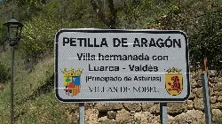 Willkommensschild in Petilla de Aragón mit Wappen und Text.