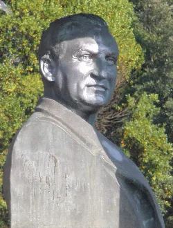 Sculpture of a man in Berango, Vizcaya, in a park with green trees.