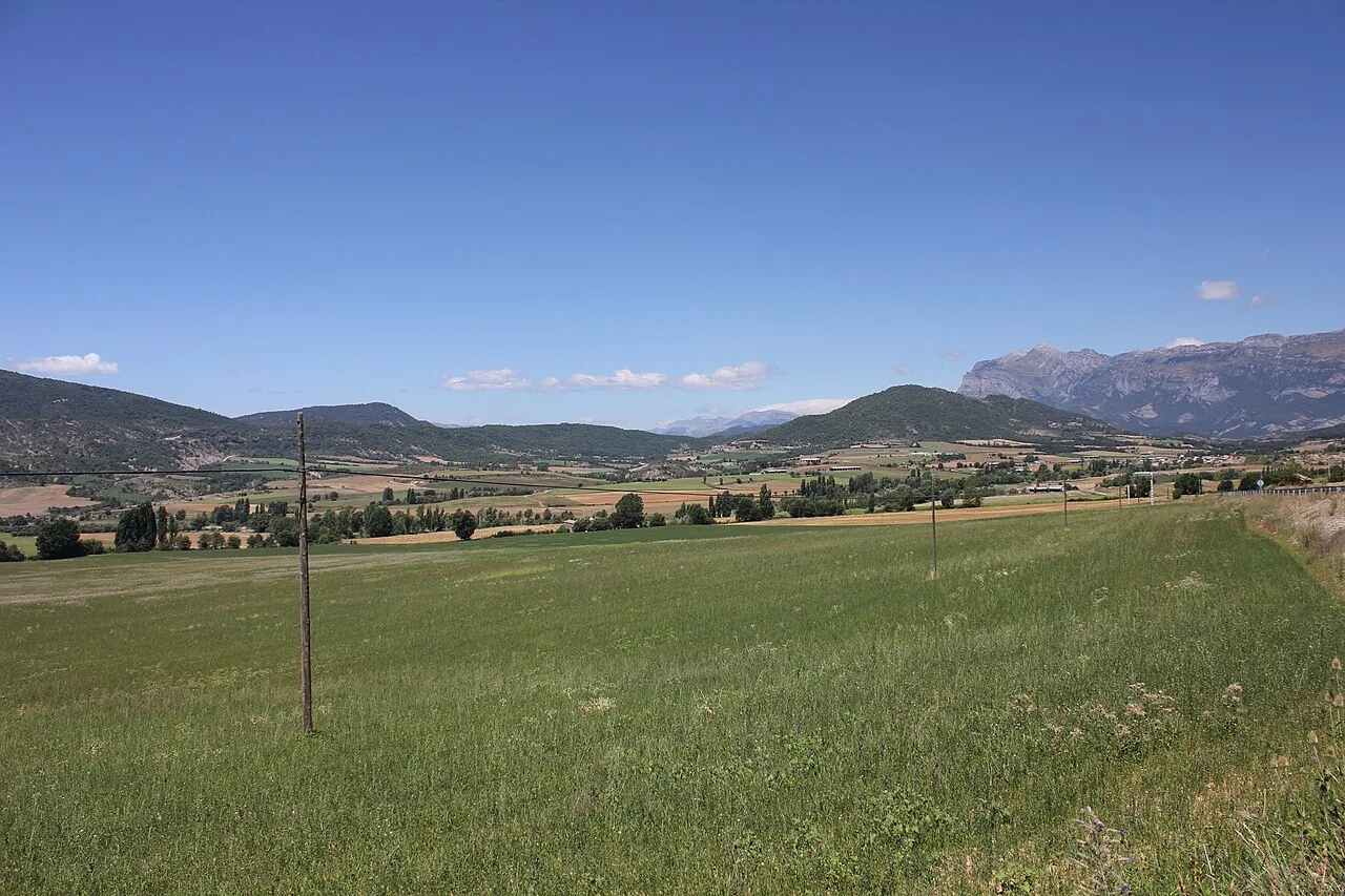 Grünes Feld mit Bergen und blauem Himmel in La Fueva.