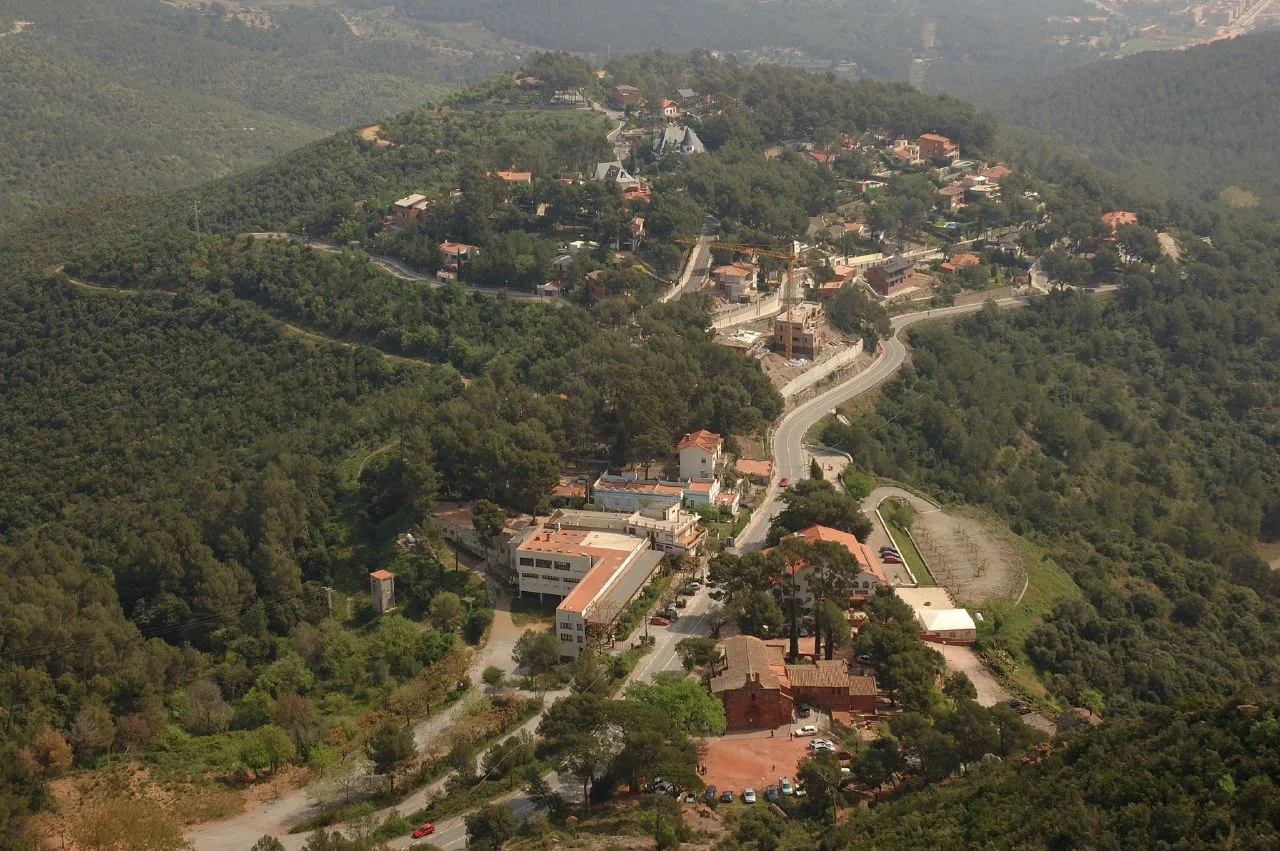 Aerial view of a neighborhood with houses and roads in a mountainous, wooded area.