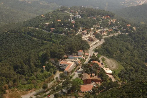 Luftaufnahme eines Viertels mit Häusern und Straßen in einer bewaldeten, bergigen Gegend.