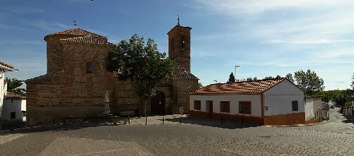 Plaza con iglesia de piedra y edificio blanco en Arcicóllar.