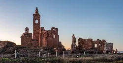 Ruins of a village with damaged buildings and a tower in the center.