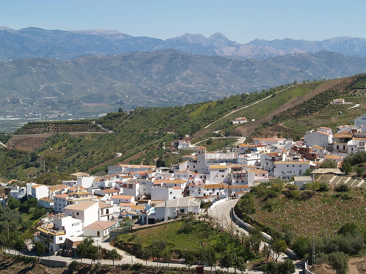 White village on hills with mountains in the background.