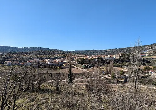 Panoramic view of Auñón with houses and hills under a blue sky.