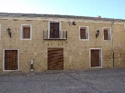 Stone building with barred windows and doors in Montesa.