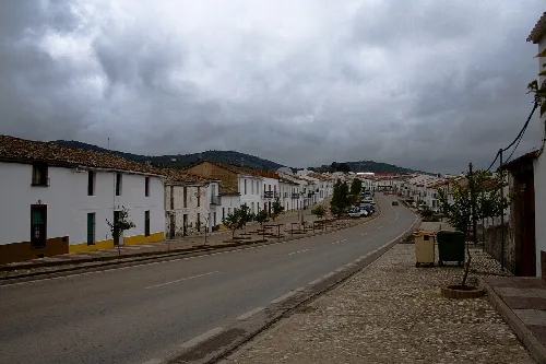 Avenida con casas blancas y cielo nublado en Cala, Huelva.