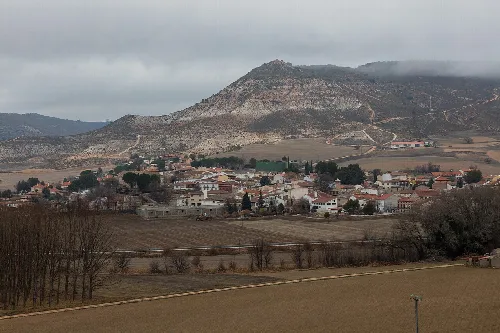 Landscape of Aranzueque with hills and houses under cloudy sky.