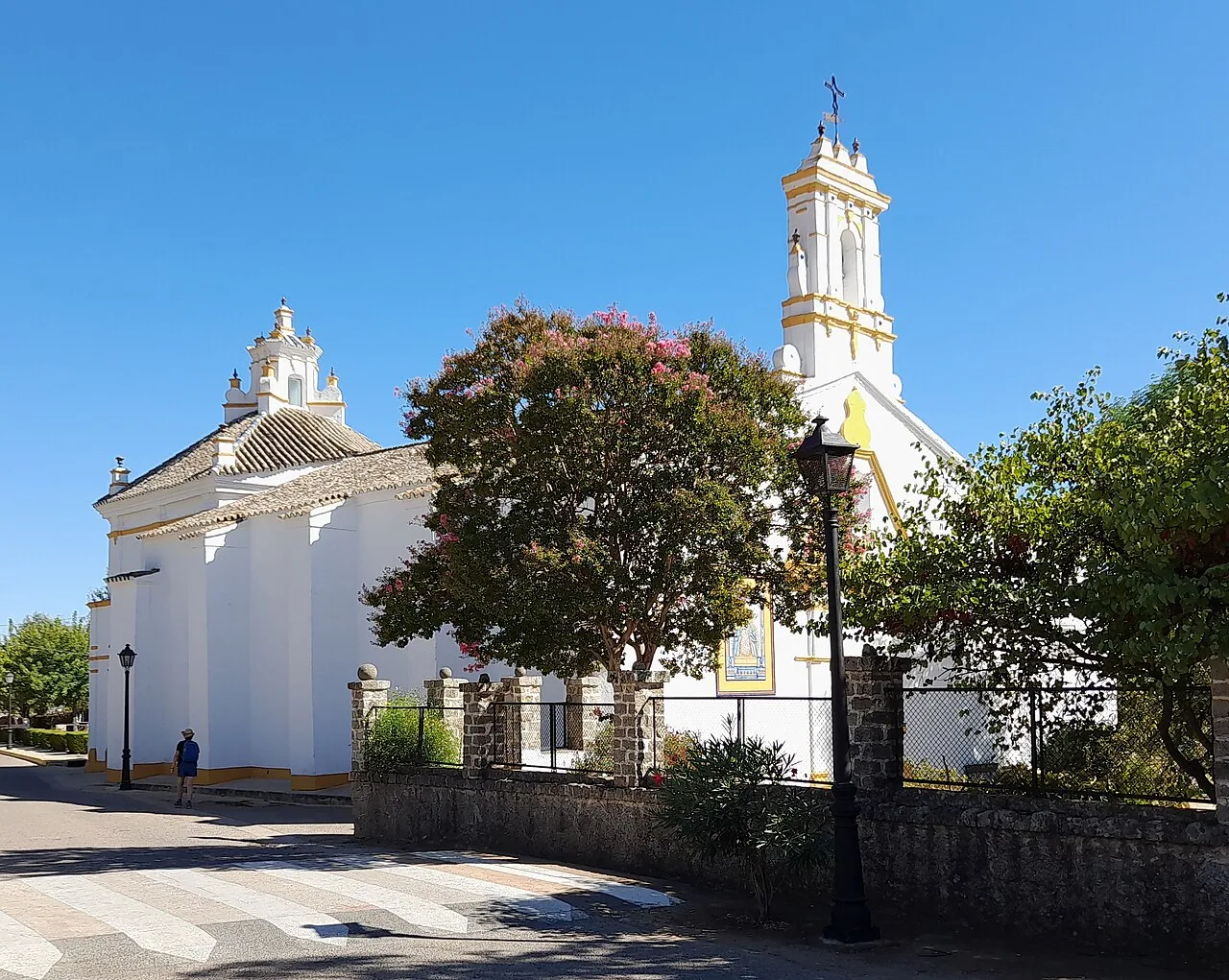 Weiße Kirche mit Glockentürmen und grünen Bäumen in El Pedroso.