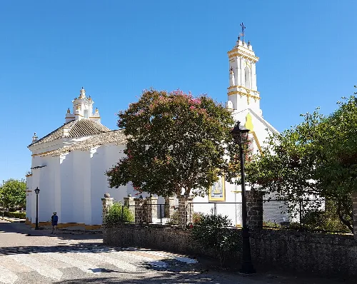 Weiße Kirche mit Glockentürmen und grünen Bäumen in El Pedroso.