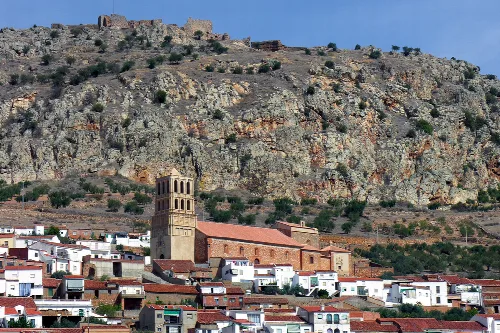 Kirche und Häuser in Hornachos mit einem felsigen Hügel dahinter.