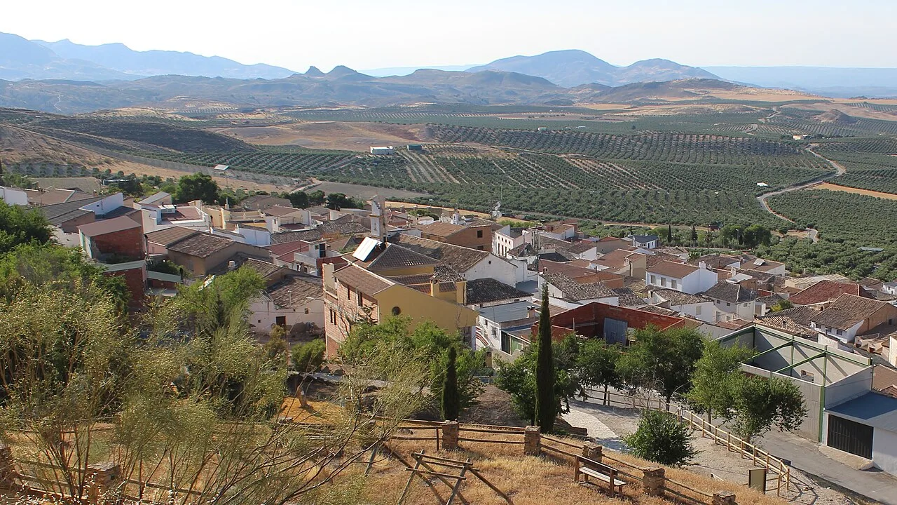 Vista panorámica de Larva, Jaén, con casas y campos en un paisaje montañoso.