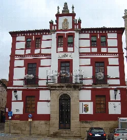 Edificio del ayuntamiento con fachada roja y blanca en Torrejoncillo.