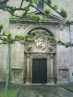 Facade of a church with sculptures and trees in the foreground.