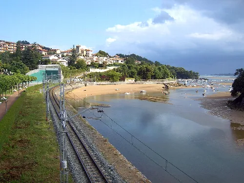 Vistas de la playa Toña en Sukarrieta con mar, embarcaciones y casas en la colina.