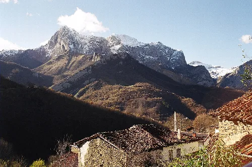 Montañas nevadas y casas en primer plano en Ponga, Asturias.